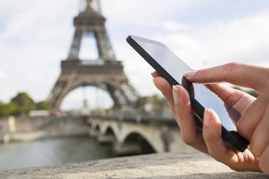 Woman in Paris using her cell phone in front of Eiffel Tower
