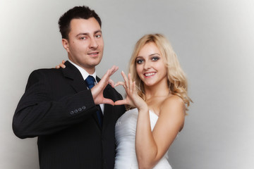 Portrait of happy bride and groom showing heart sign
