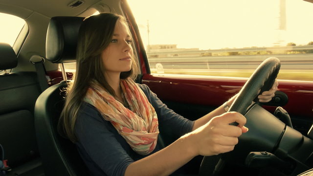 brunette girl driving a car, gorgeous sun flare and grading. Occ