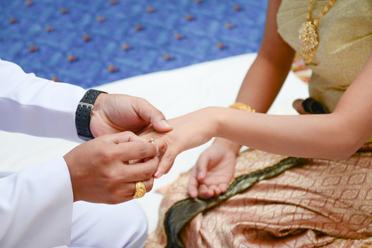 Groom wears a diamond ring onto the brides hand