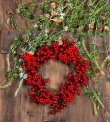 green christmas tree branches and wreath from red berries