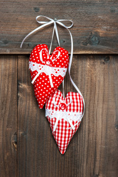 two red hearts hanging over wooden background