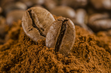 coffee seeds or beans over ground coffee close up macro