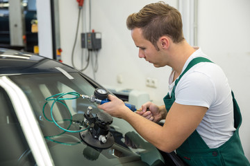 Glazier repairing stone-chipping damage on car's windshield