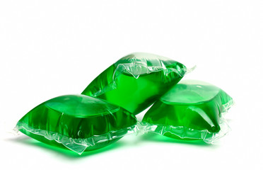 Three green laundry detergent capsules on white
