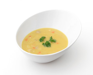 A bowl of yellow split-pea soup on a white background