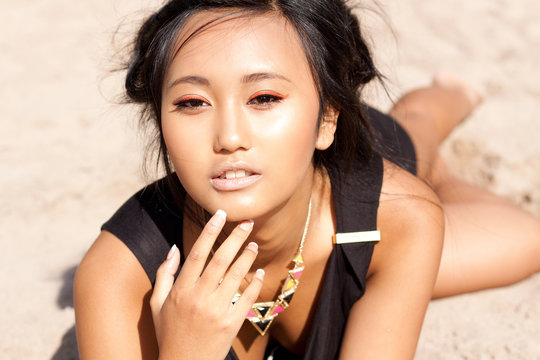 junge attraktive sinnliche asiatische frau im sand liegend