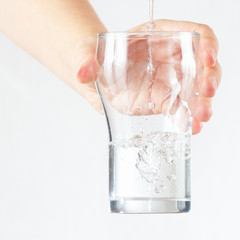 Female hand holding a glass of fresh water is poured