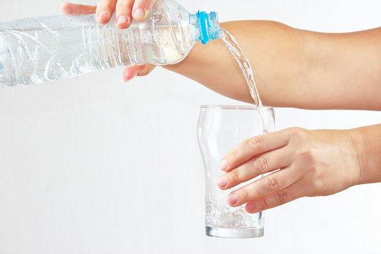 Female hand pour water into a glass from bottle