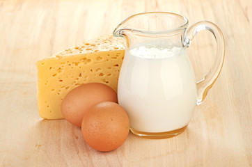 Big piece of cheese, glass jug with milk