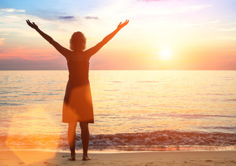 Young woman on the sea beach meets a beautiful sunset.