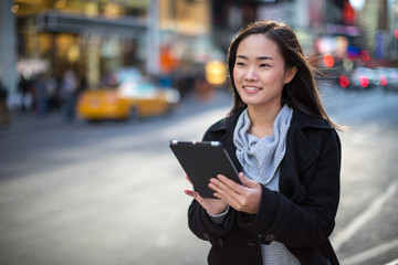 Asian woman in New York City using ipad tablet pc