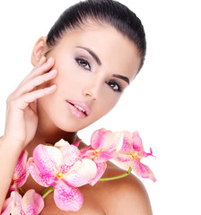 Beautiful face of  woman with healthy skin and pink flowers