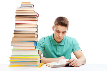 Student studying at a table with a stack of books