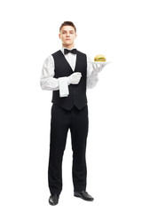 Young serious waiter holding hamburger on plate
