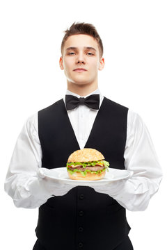 Young Serious Waiter Holding Burger On Plate