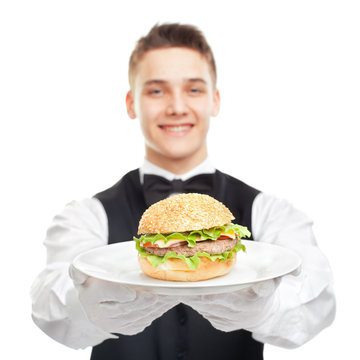 Young Happy Smiling Waiter Holding Hamburger On Plate