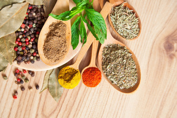 Spices in wooden spoons on brown