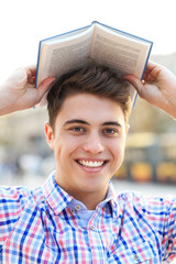 Young man with book over his head