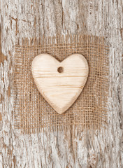 Wooden heart with burlap textile on the old wood
