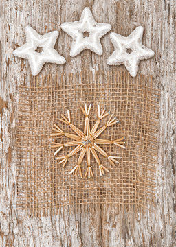 Straw snowflake with stars on textile and old wood
