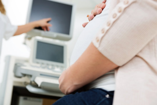 Pregnant Woman With Doctor Pointing At Ultrasound Scan