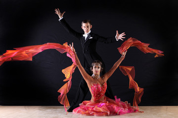 Latino dancers in ballroom against on black background