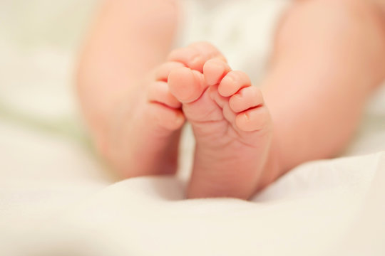 Small newborn baby feet on the bed