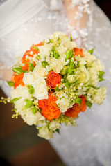 Bride holding weeding flowers in green and arange