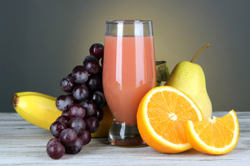 Glass of fresh juice on table on gray background