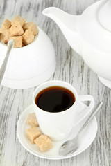 Cup of coffee, teapot and sugar-bowl on color wooden background