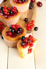 Tasty muffins with berries on white wooden table