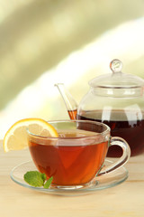 Cup of tea with lemon on table on light background