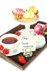 Cup of tea with cakes on wooden tray isolated on white
