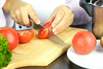 Cook hands cutting tomato