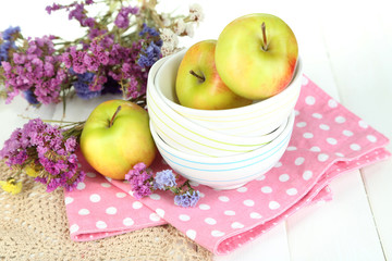 Juicy apples on plate on white wooden table