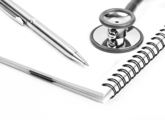 Stethoscope and silver pen on meadical notebook