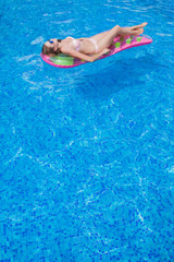 beautiful girl floating on a mattress in the sea or swimming poo
