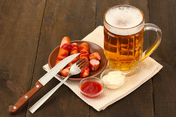 Beer and grilled sausages on wooden background