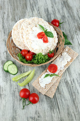 Tasty crispbreads with vegetables on wooden background