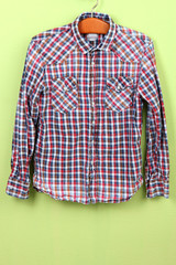 Male shirt on wooden hanger on wall background