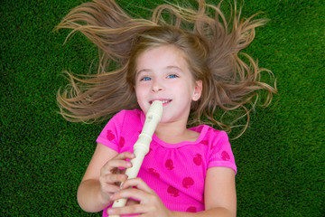 Blond kid children girl playing flute lying on grass © lunamarina
