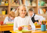 Little schoolgirl sitting behind school desk