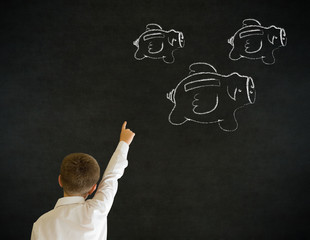 Business boy with flying piggy banks on blackboard background