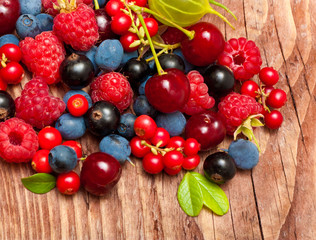 Naklejka na ściany i meble Different type of wild berry fruits on wooden background.