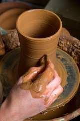 hands of a potter, creating an earthen jar on the circle
