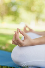 Mid section of young woman meditating sitting on an exercise mat