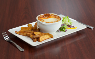 Side view of lasagna with salad and potatoes