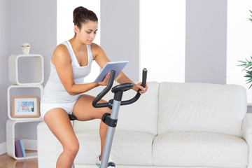 Concentrated slender woman training on an exercise bike while us