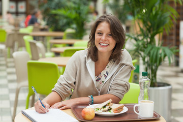 Obraz na płótnie Canvas Student doing homework while having breakfast in the cafeteria